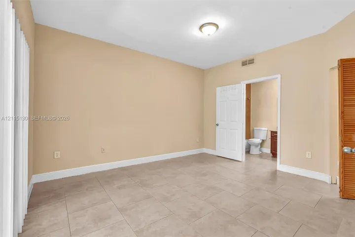 Neutral-toned interior room featuring large-format ceramic tile flooring, a six-panel interior door, and a wooden bi-fold door