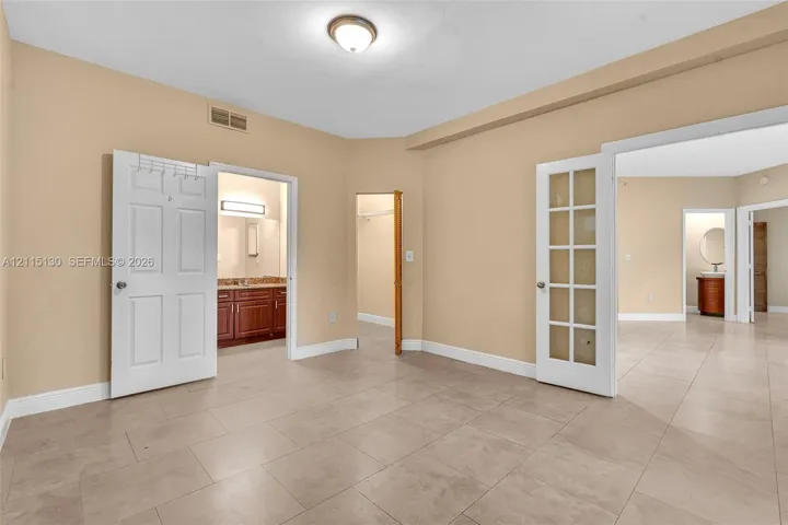 Neutral-toned tile flooring, white six-panel interior doors, and a glass-paneled French door