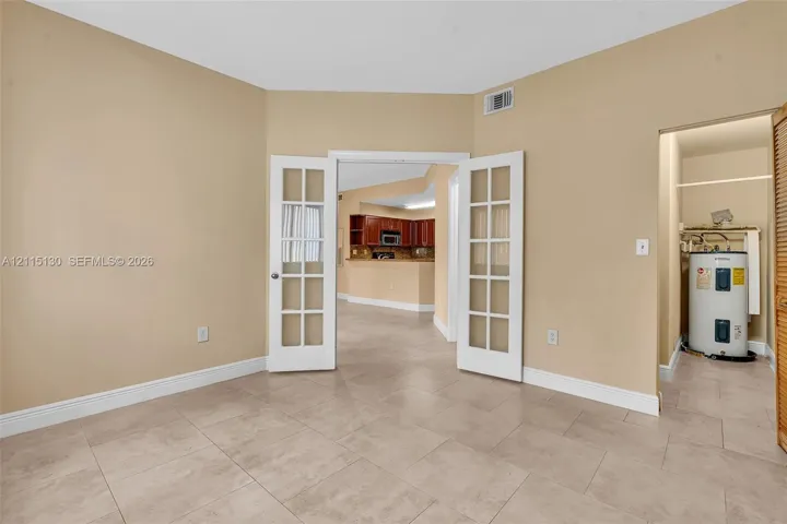 Room featuring large-format ceramic tile flooring and white French doors with glass panes