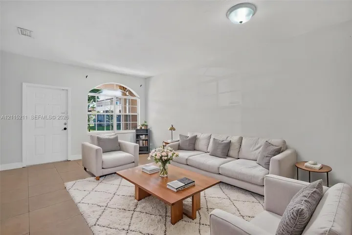 Neutral-toned tile flooring, arched window with a grid pattern, and flush-mount overhead lighting
