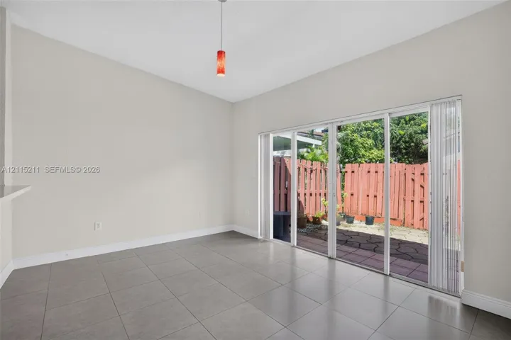 Large-format ceramic tile flooring, neutral wall tones, multi-panel sliding glass door, and hanging pendant light fixture