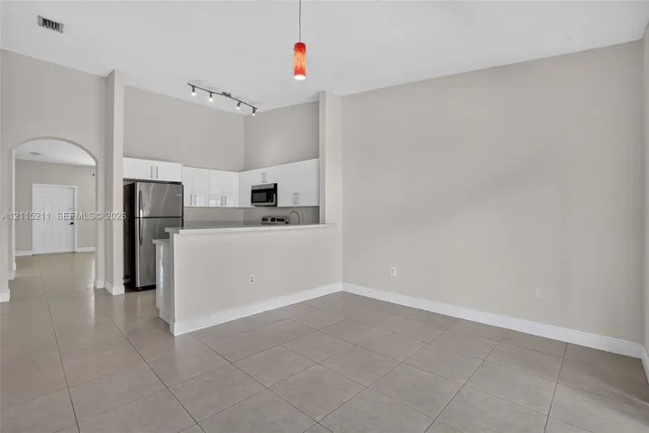 Kitchen featuring white flat-panel cabinetry, stainless steel appliances, a breakfast bar, and neutral floor tiling throughout