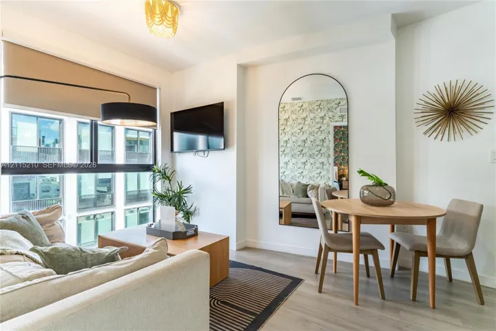 Floor-to-ceiling windows, wood-finish flooring, built-in television mount, and full-length arched wall mirror