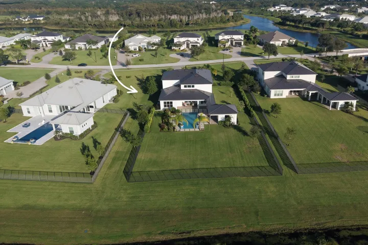 Aerial perspective of property featuring an expansive fenced backyard, private swimming pool, covered lanai, and multi-level roofline