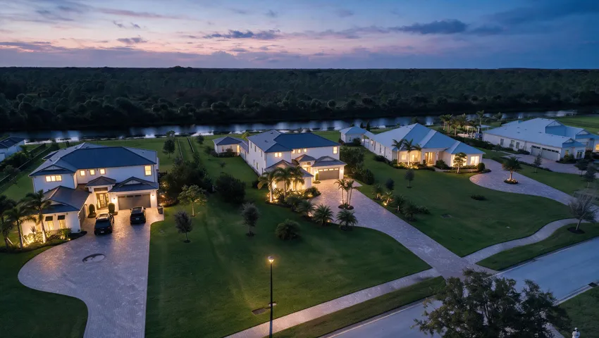 Aerial perspective of waterfront properties featuring multi-story residences, paved driveways, hipped rooflines, and manicured lawns