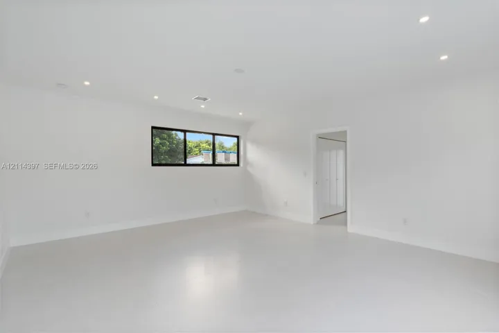 Minimalist room featuring neutral large-format tile flooring, recessed ceiling lighting, and a horizontal window with a dark frame