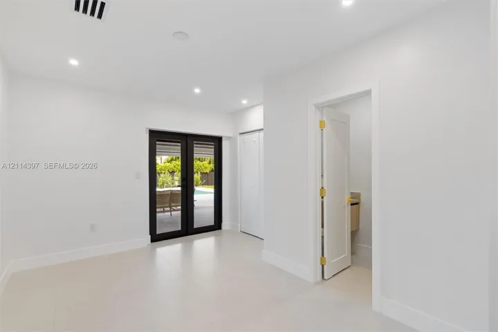 Interior space featuring light-toned tile flooring, recessed ceiling lighting, a closet with double-panel doors, and black-framed French doors