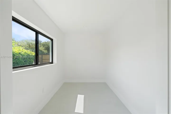 Minimalist interior space featuring large-format tile flooring, high-contrast dark-framed windows, and recessed ceiling lighting