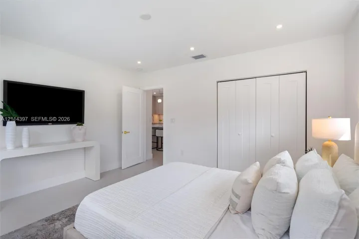 Room featuring crisp neutral walls, recessed lighting, a built-in wall-mounted console, and a closet with multi-panel doors