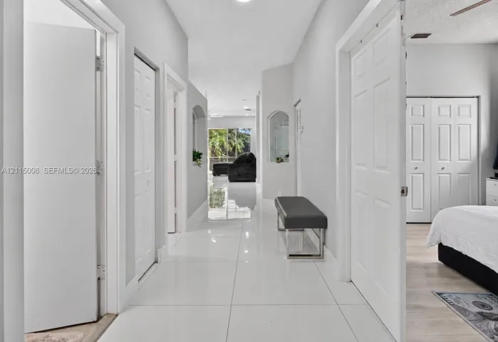Hallway featuring glossy tile flooring, neutral wall color, arched wall niches, and paneled interior doors