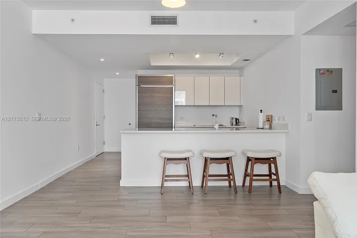 Kitchen featuring flat-panel cabinetry, wood-finish paneling on a built-in refrigerator, stone-surface countertop, recessed ceiling lighting, and wood-finish flooring