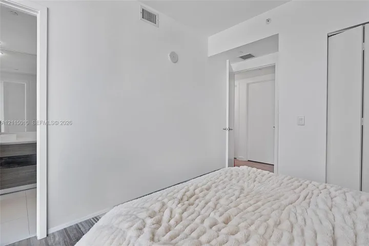 Neutral interior featuring wood-finish flooring, white walls, and a multi-panel closet door
