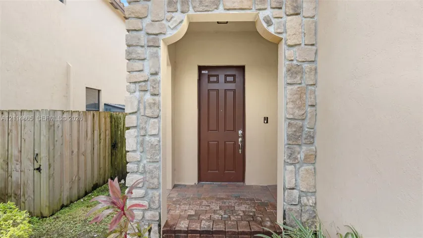 Entryway featuring a stone-clad arched portico, paver flooring, and a six-panel door