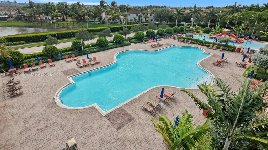 Large swimming pool featuring a brick-paved deck, secondary water play area, and perimeter landscaping