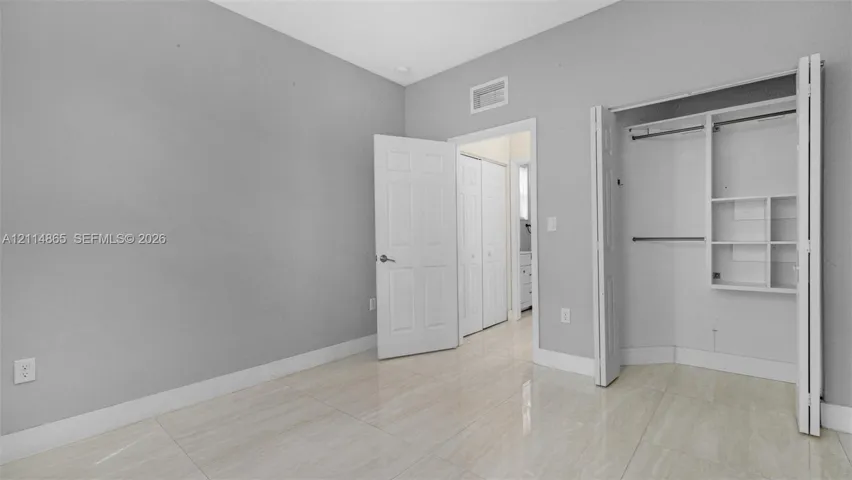 1st floor bedroom! Perfect guest/in-law space Interior space featuring neutral wall paint, polished tile flooring, and a walk-in closet with built-in shelving