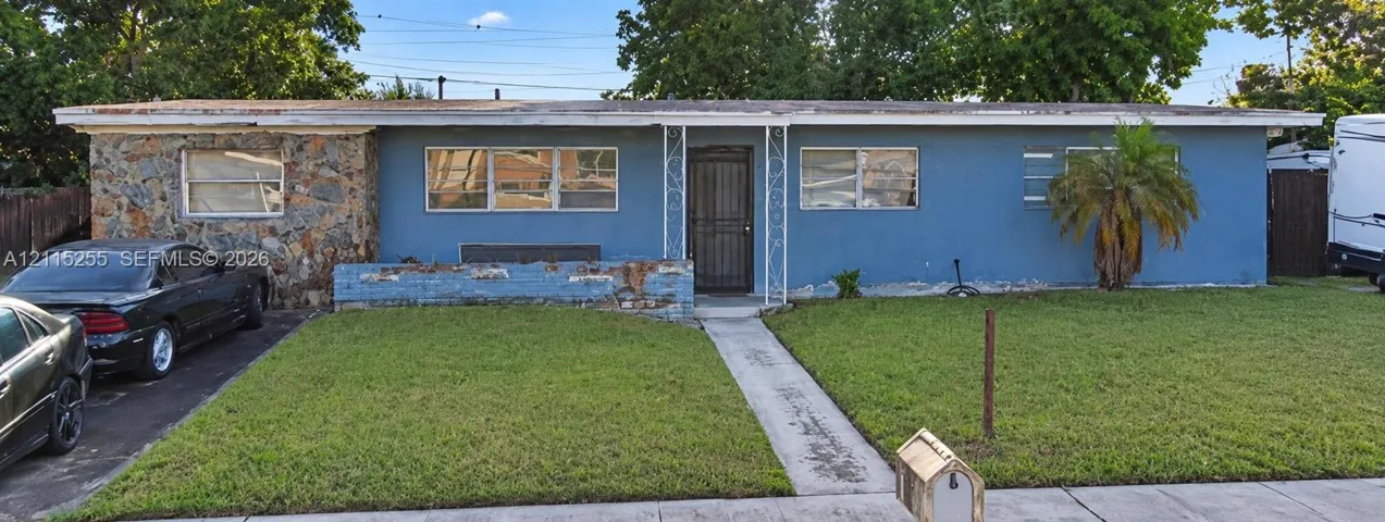 Single-story exterior featuring a stone-clad facade, blue painted siding, horizontal windows, a decorative metal porch support, and a concrete walkway