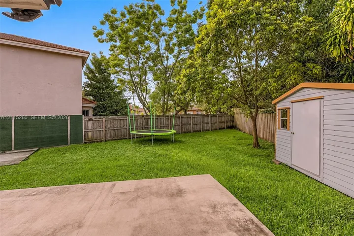 Backyard featuring a concrete patio, wood-style privacy fencing, and a detached storage shed