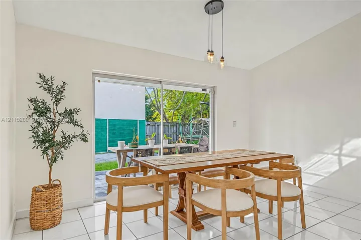 Ceramic tile flooring, multi-light hanging pendant fixture, and large sliding glass door with exterior access
