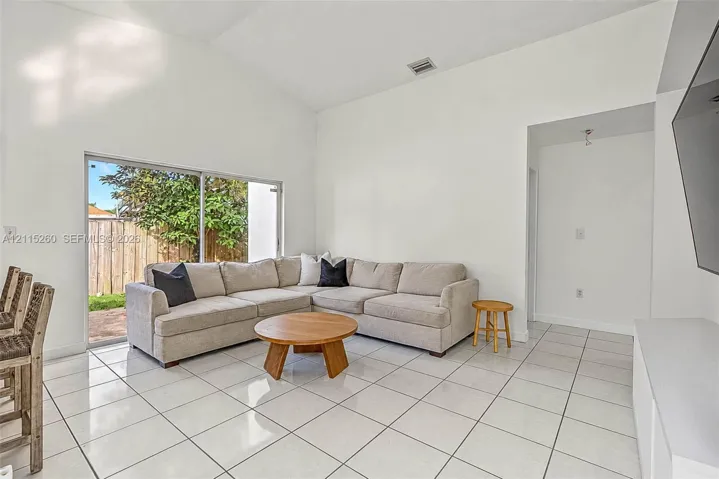 Vaulted ceiling, large sliding glass doors, and polished tile flooring