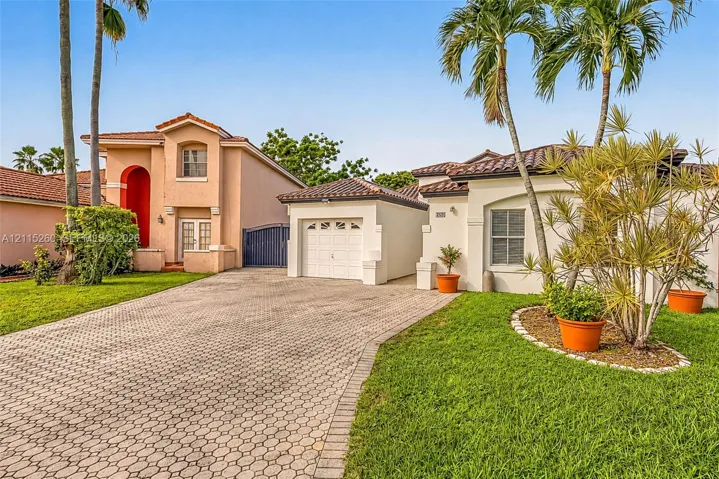 Stucco exterior featuring a paved driveway, tile roofing, and mature palm trees
