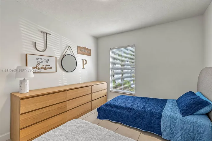 Room featuring neutral walls, large-format tile flooring, and a single-pane window with horizontal blinds