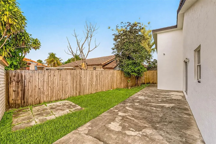 Private backyard featuring a concrete patio, a grass lawn, and wood privacy fencing