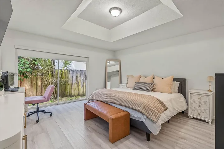 Tray ceiling, wood-finish flooring, and sliding glass doors leading to exterior space