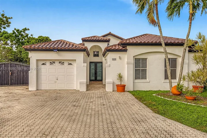 Stucco exterior featuring a clay tile roof, arched entryway, paved driveway, and single-car garage