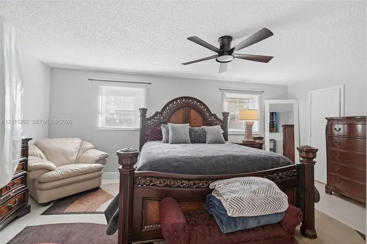 Neutral-toned room featuring a central ceiling fan with an integrated light fixture and dual windows with metal rods