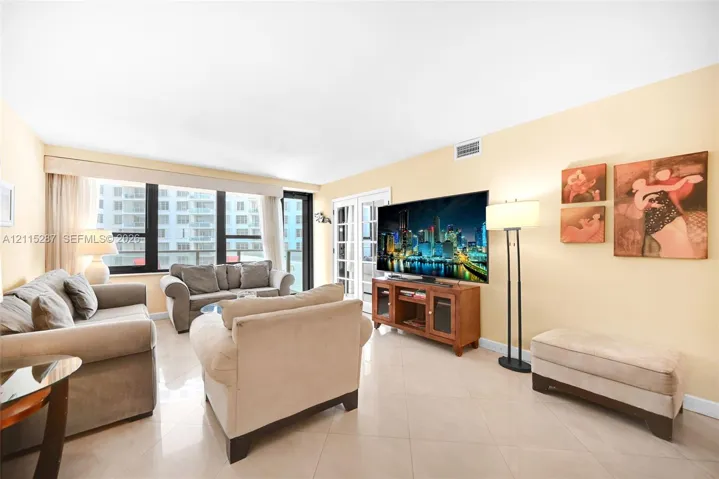 Living area featuring large-format ceramic tile flooring, floor-to-ceiling windows, and glass-paneled patio doors