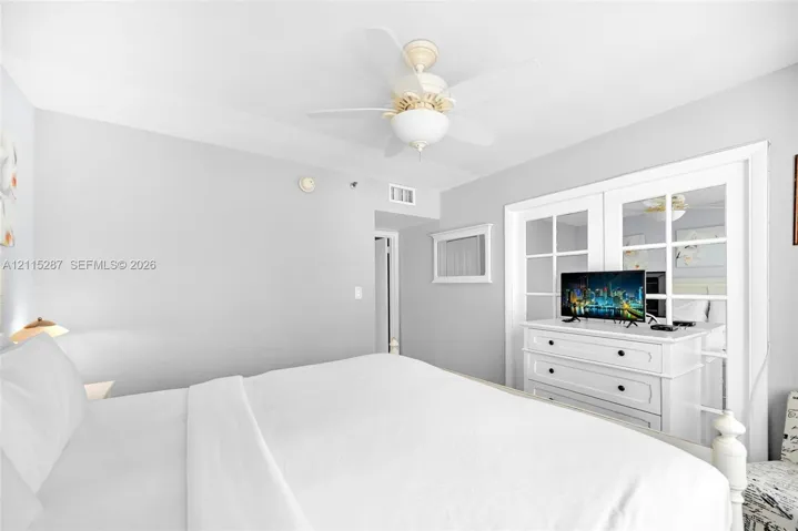 Neutral-toned interior featuring a ceiling fan with integrated lighting and double glass-paneled closet doors