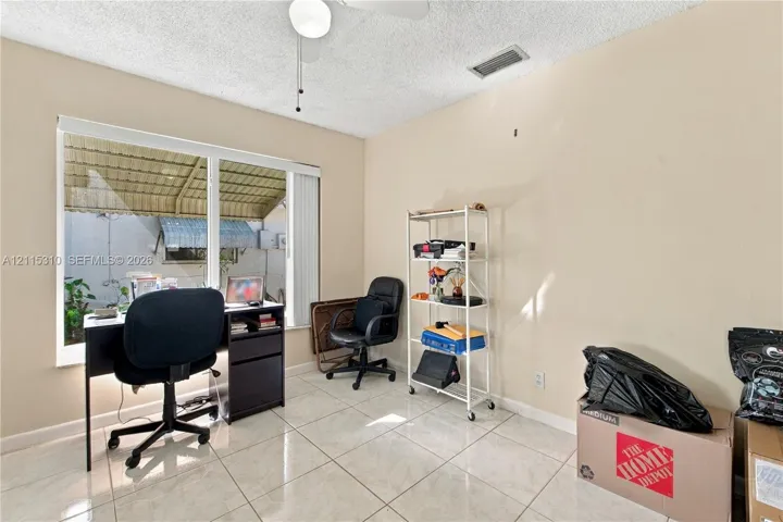 Interior space featuring large-format ceramic tile flooring, neutral wall paint, and a ceiling-mounted light fixture with an integrated fan