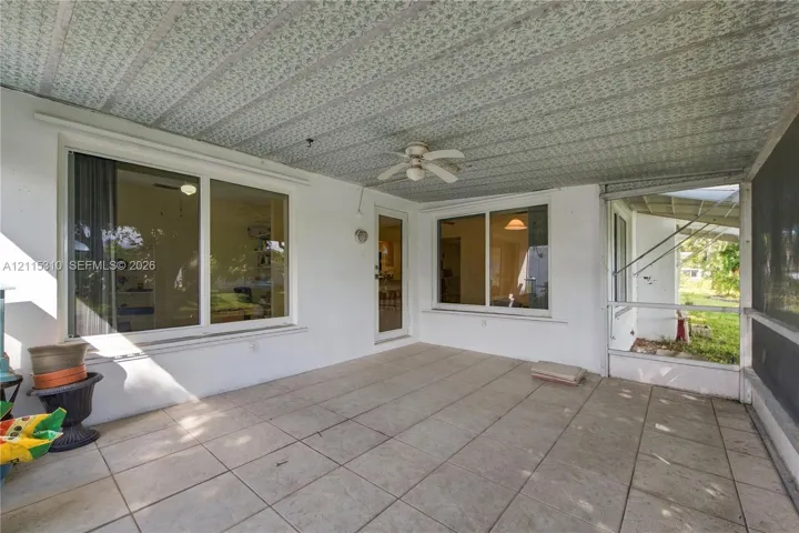 Covered patio featuring large-format ceramic tile flooring, a textured ceiling with an integrated ceiling fan, and large windows