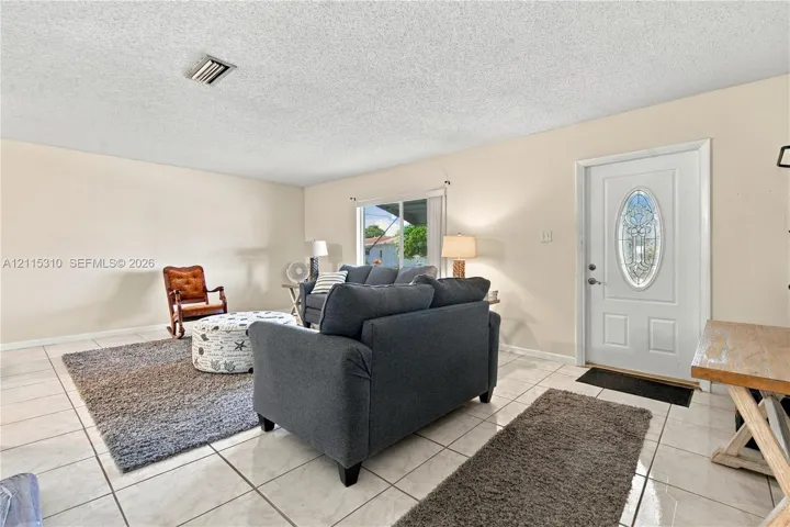 Light-toned tile flooring, white entry door with oval decorative glass insert, and sliding glass exterior door
