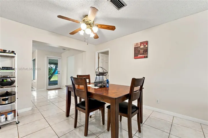 Ceramic tile flooring, ceiling fan with integrated lighting, and glass-paneled exterior door