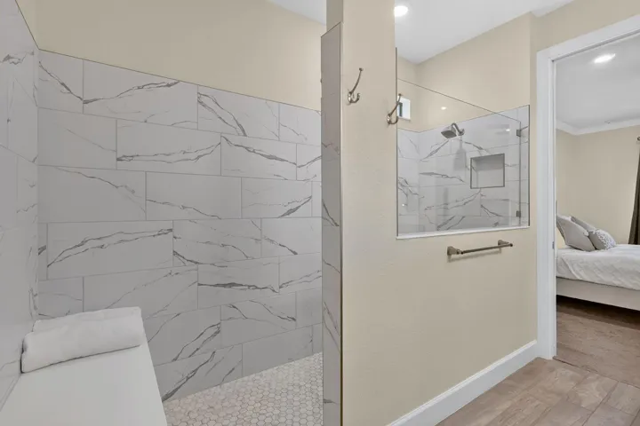 A spacious glass shower with a built-in bench offers a comfortable place to reset before retreating to the bedroom