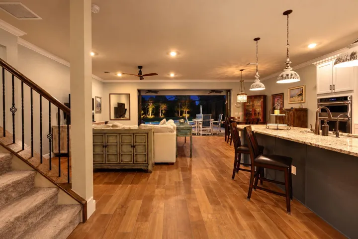 Wood-look tile, crown molding and an open staircase bring warmth and character to a living room made for staying awhile