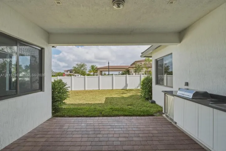 Covered patio with outdoor kitchen and built-in grill.