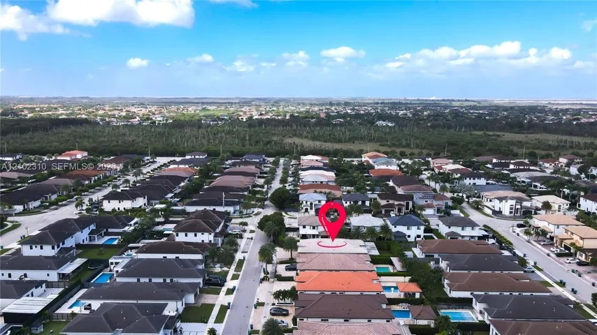 Aerial perspective of a multi-story residence featuring a tile roof, a private swimming pool, and an enclosed rear patio, situated within a master-planned community