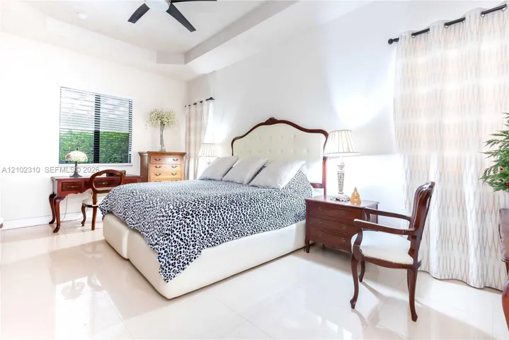 Tray ceiling, neutral tile flooring, and matte black ceiling fan