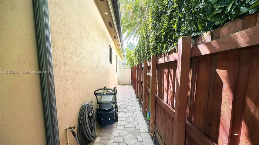 Side yard featuring a paved walkway, stucco exterior wall, and wood privacy fencing