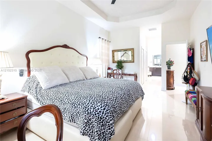 Tray ceiling with integrated fan, polished tile flooring, and neutral wall tones