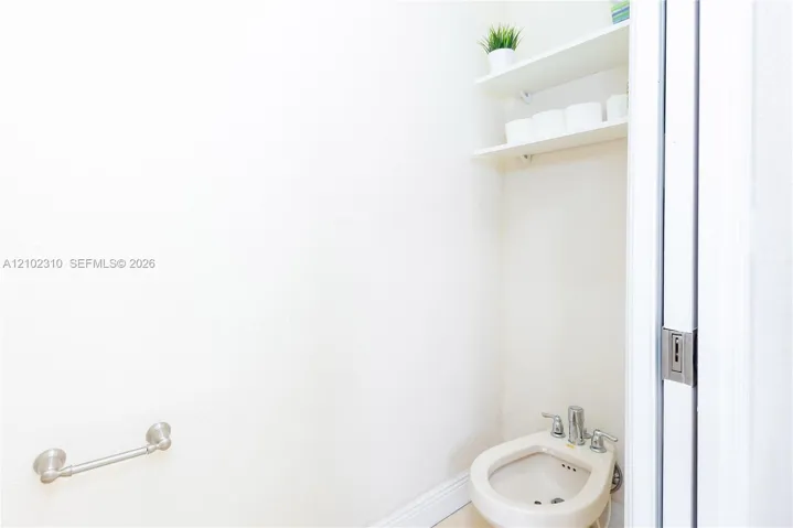 Bidet with chrome fixtures, two wall-mounted shelves, and a wall-mounted metal towel bar