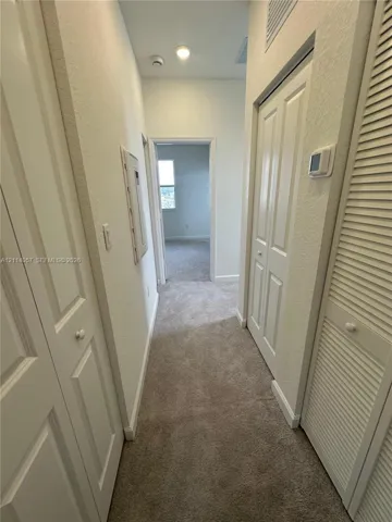 Neutral-toned wall-to-wall carpeting, white paneled interior doors, and louvered closet doors