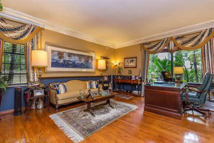 Hardwood flooring, crown molding, chair rail, and multiple oversized windows with greenery exposure