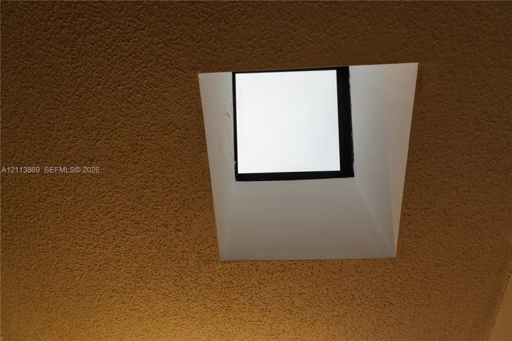 Square ceiling-mounted skylight with a white recessed frame and textured ceiling finish