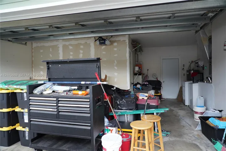 Attached garage featuring concrete flooring, an automated overhead door opener, and a dedicated laundry area with utility hookups