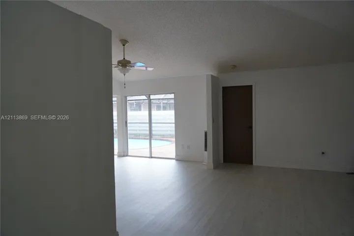 Interior space featuring light-toned flooring, sliding glass doors, a ceiling fan, and a neutral color palette