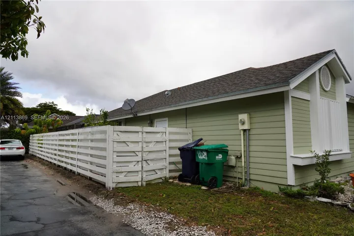 Horizontal lap siding exterior with a gable roofline and white wooden privacy fencing