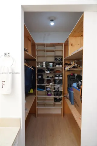 Walk-in closet featuring built-in wooden shelving, integrated storage cubbies, and wood-finish flooring